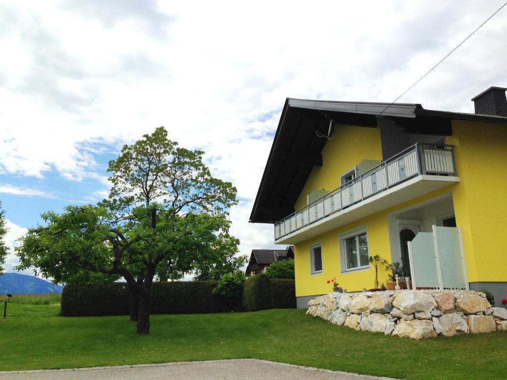 Casa amarilla con balcón y árbol en Apartments Urschitz, en Drobollach am Faakersee