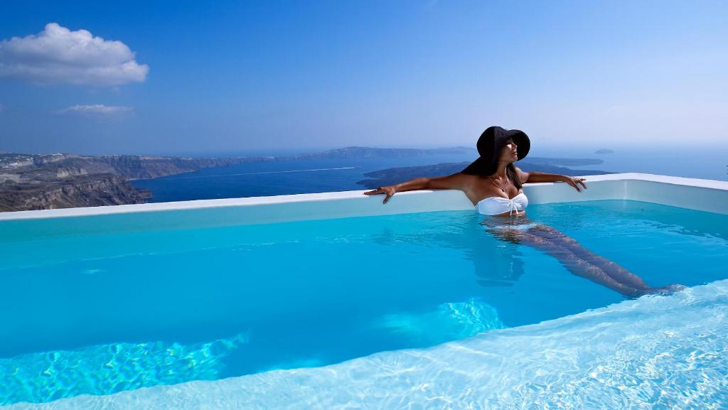 a woman is sitting in a swimming pool at Alexander Villas in Imerovigli