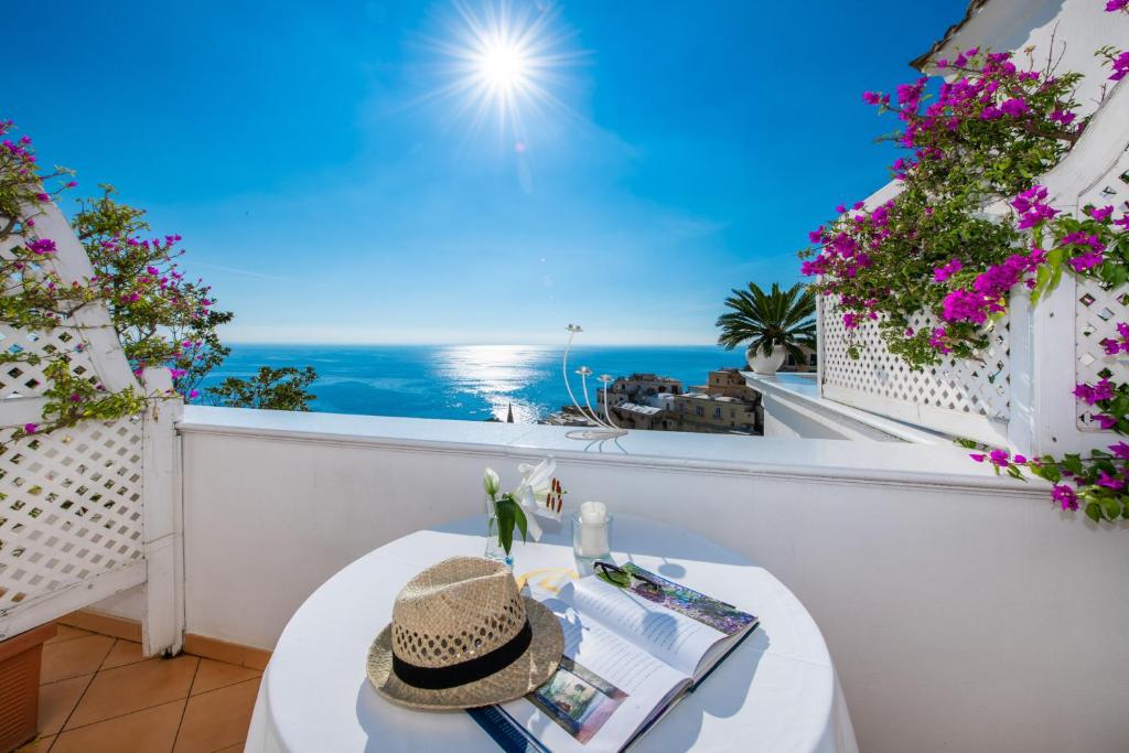 una mesa con un sombrero en el balcón con vistas al océano en Villa Yiara, en Positano