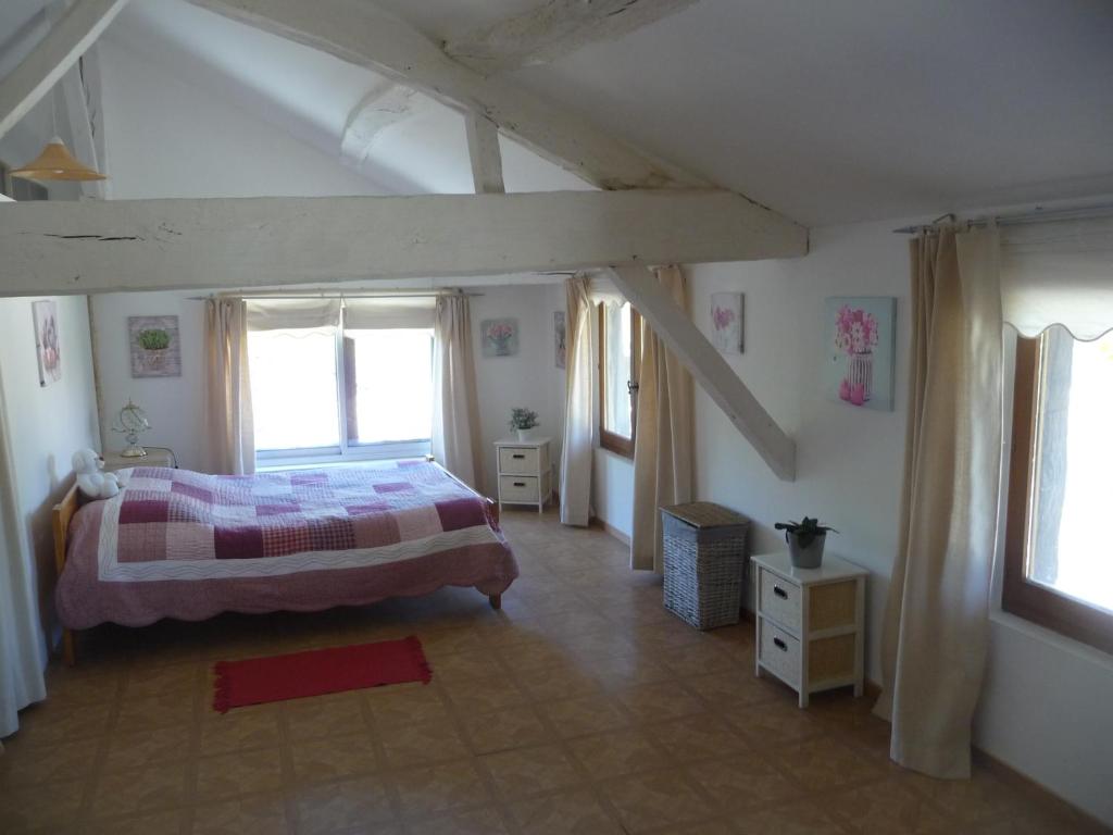 une chambre avec un lit et deux fenêtres dans l'établissement Les Tuileries, à Ponteyraud