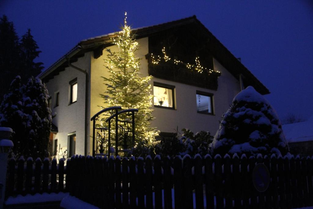 ein Haus mit einem Weihnachtsbaum vor einem Zaun in der Unterkunft Apartment am Nationalpark Bayerwald in Lindberg
