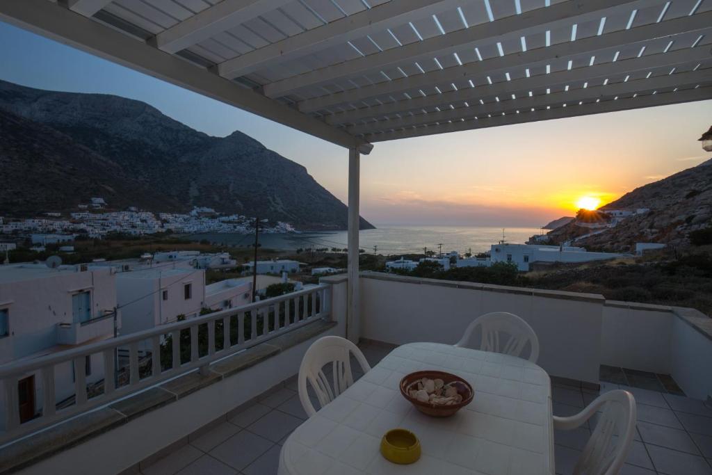 a balcony with a table and chairs and the sunset at Litsa Rooms in Kamares