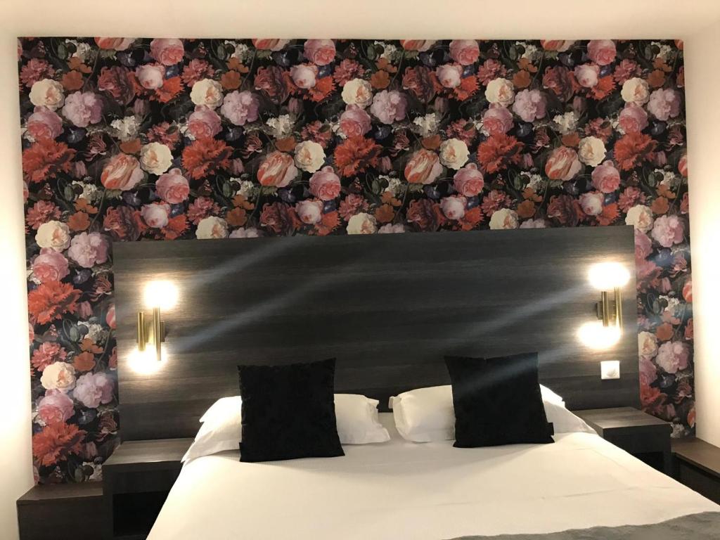 a bedroom with a bed with a floral wall at Hôtel Le G (ex Le Genève) in Nice