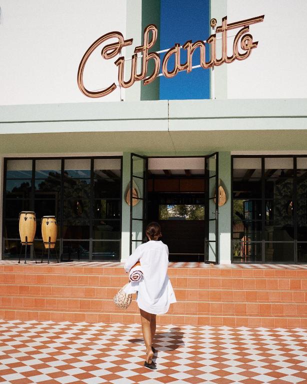 a woman in a white dress walking in front of a building at Cubanito Ibiza in San Antonio