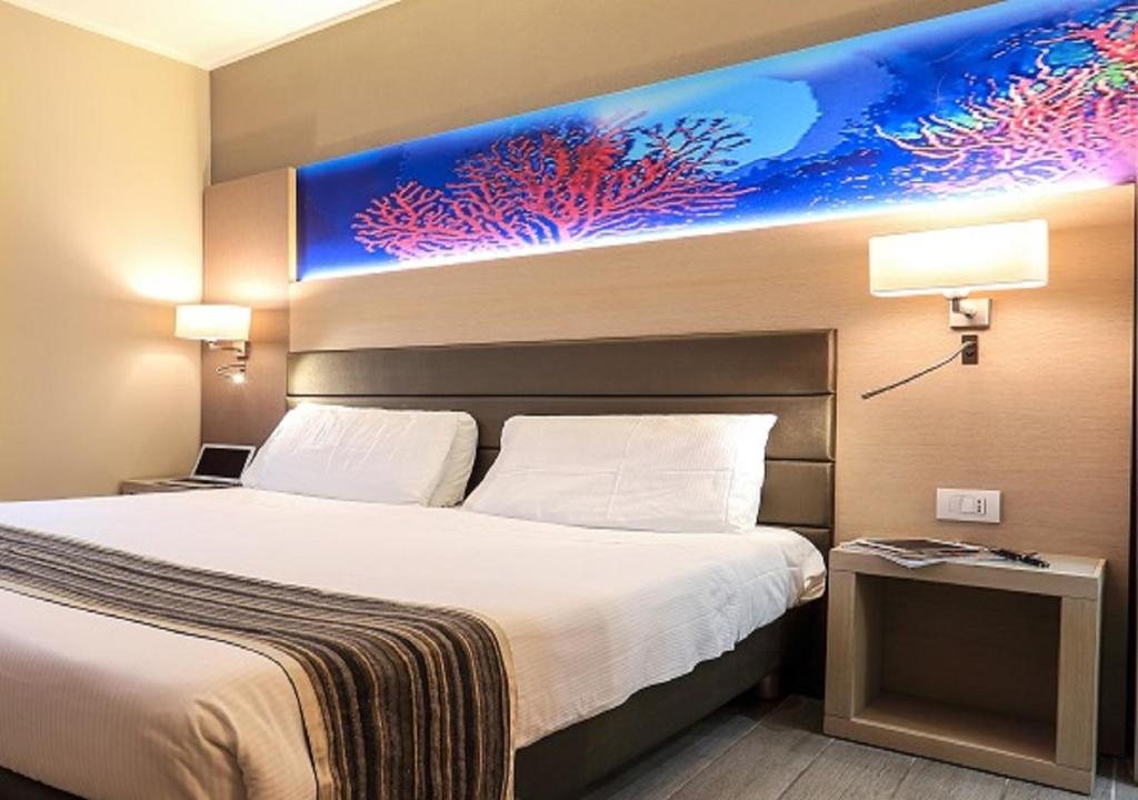 a bedroom with a large bed with a painting on the wall at Alma di Alghero Hotel in Alghero
