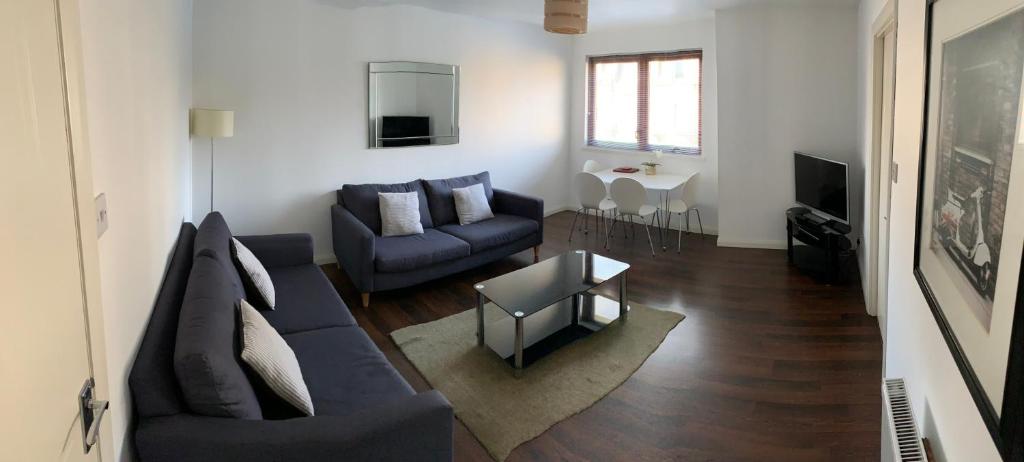 a living room with a blue couch and a table at Aberdeen Serviced Apartments - Bloomfield in Aberdeen