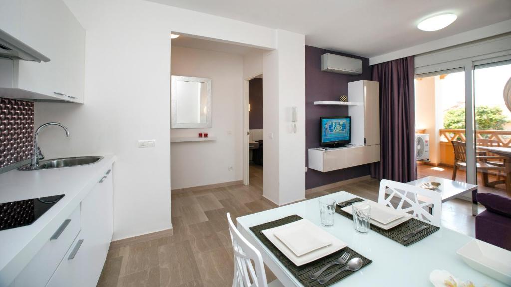 a kitchen and living room with a table and a television at Leo Canela in Isla Canela