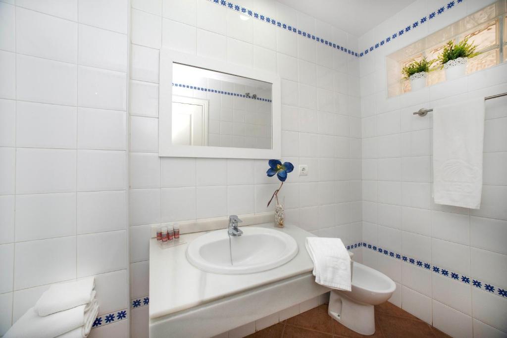 a white bathroom with a sink and a toilet at Leo Canela in Isla Canela