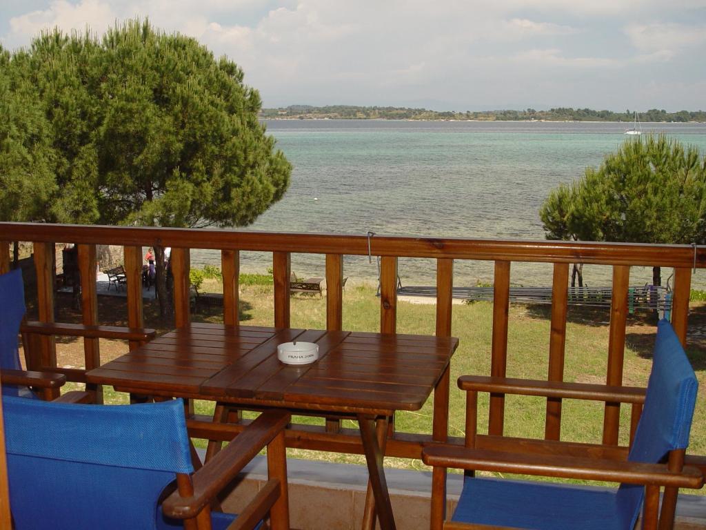 a wooden table and chairs on a balcony with the water at Studios Efi beach in Vourvourou
