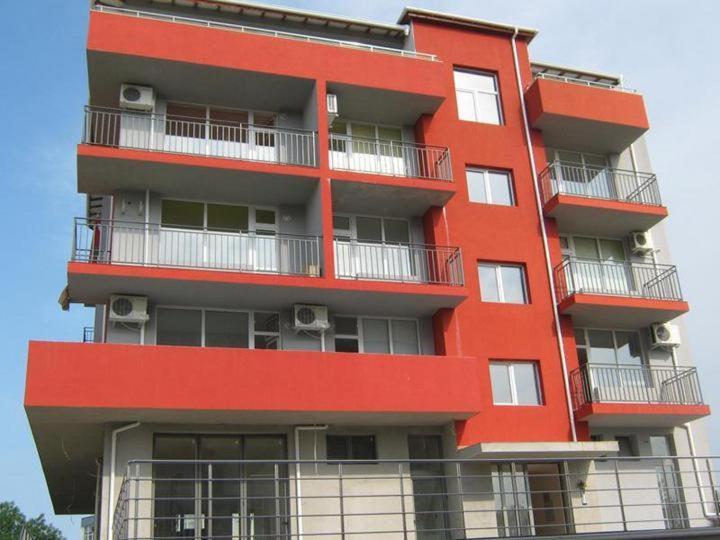 um edifício vermelho com varandas ao lado em Stefani Apartments em Primorsko