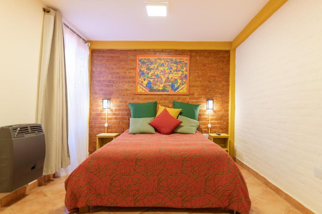 1 dormitorio con 1 cama con colcha roja en Samaná Departamentos en El Bolsón