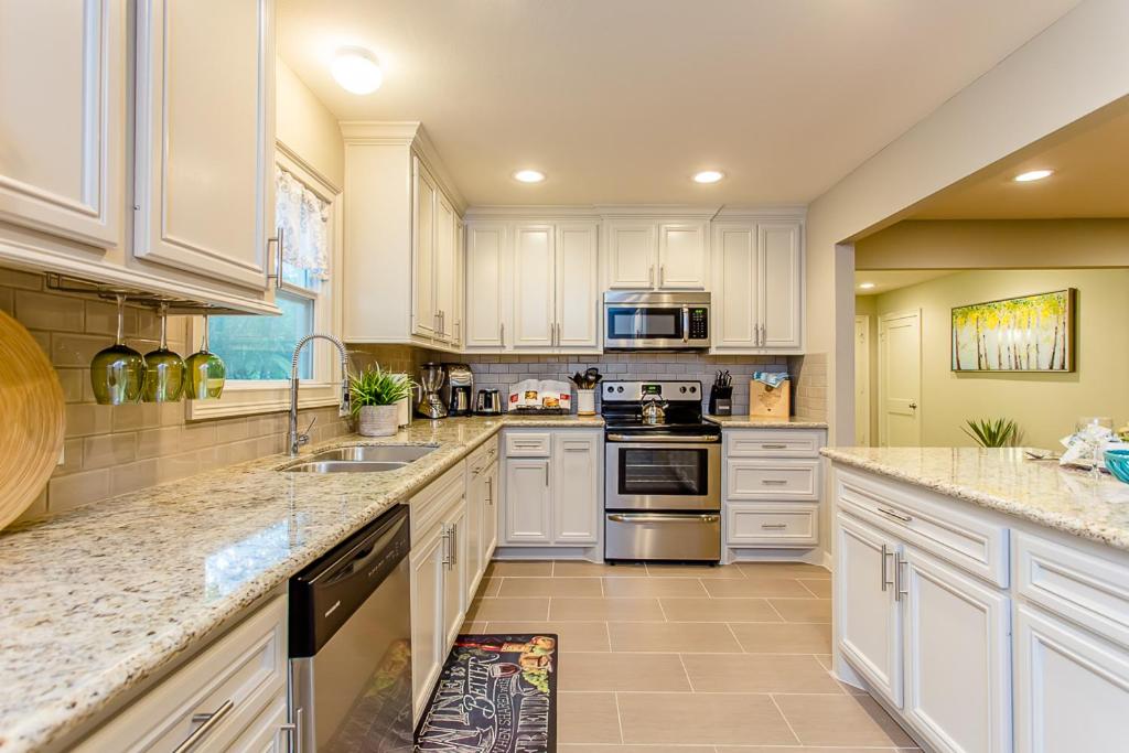uma grande cozinha com armários e electrodomésticos brancos em The Blue Door Bungalow - Luxury Home Downtown Houston em Houston