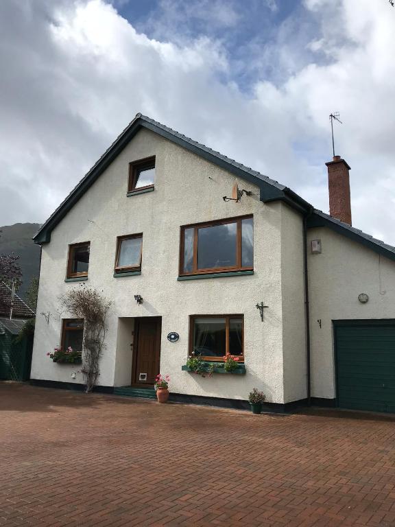 a white house with windows and a garage at The Woolly Rock in North Ballachulish