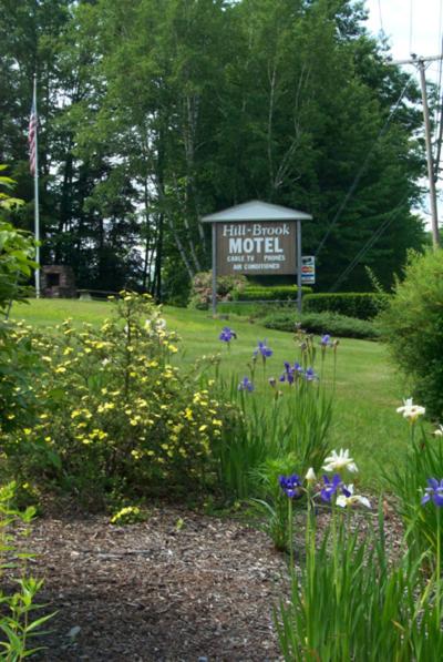 una señal en medio de un campo con flores en Hill-Brook Motel, en Bedford