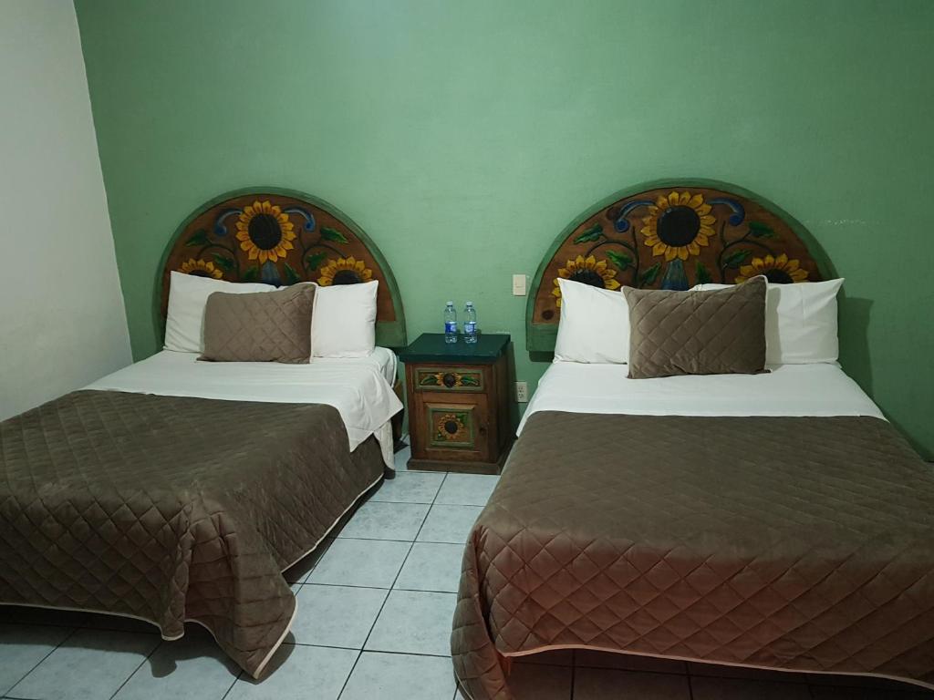 a hotel room with two beds and a night stand at Hotel Meson Mariano Matamoros in Querétaro