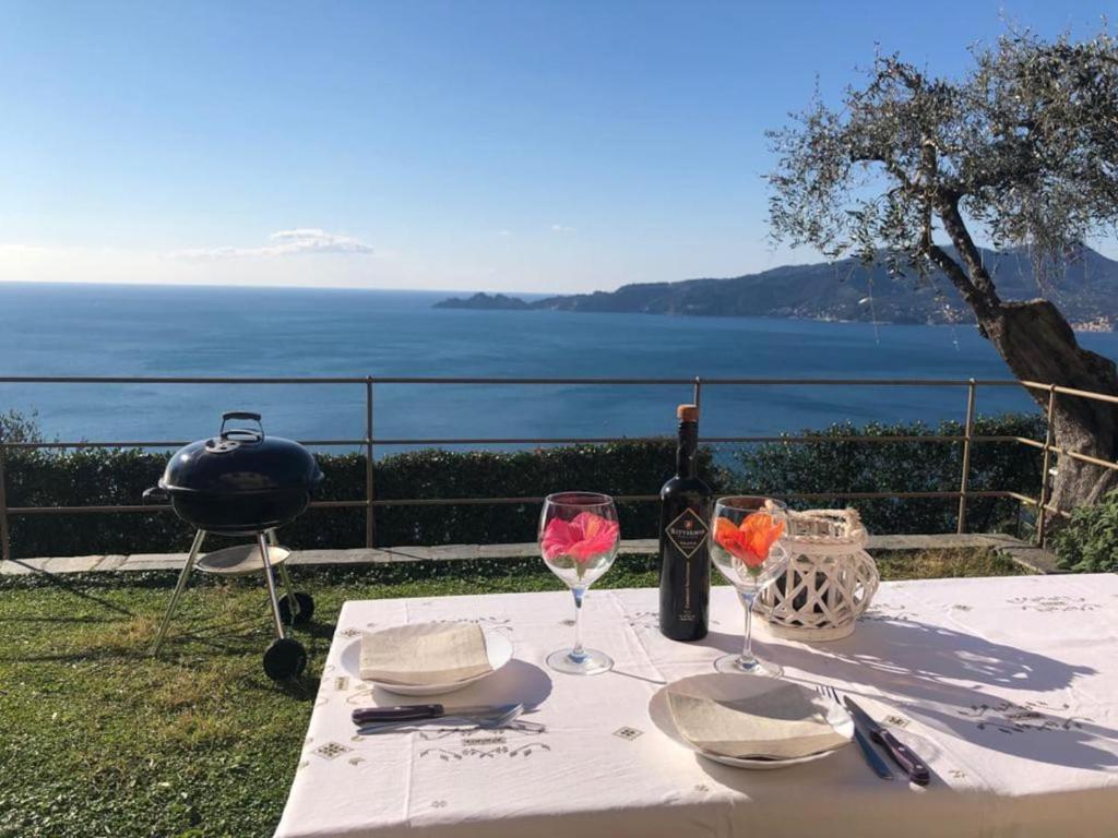 a table with wine glasses and a grill with a view of the ocean at Villa del Sol in Zoagli