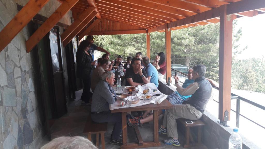 un gruppo di persone seduti a un tavolo in un ristorante di Koromilia refuge a Díon