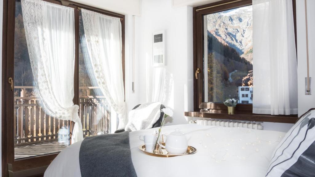 um quarto com uma cama e uma grande janela em L'Atelier du Temps - PanoramAlps Apartment em Courmayeur