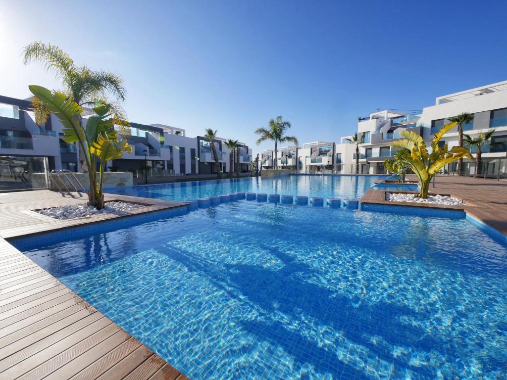una gran piscina con palmeras y edificios en oasis beach casa Georgio, en Guardamar del Segura