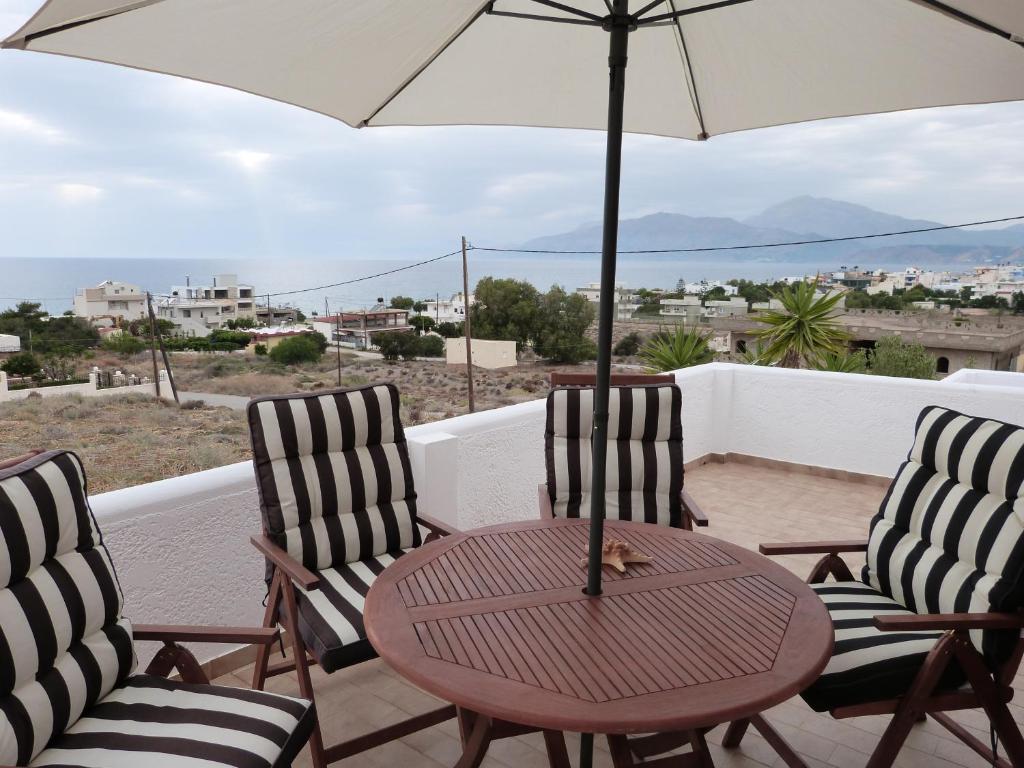 a table and chairs with an umbrella on a balcony at Theathina in Kalamaki Heraklion