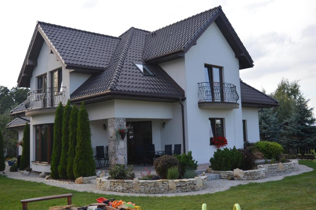 a white house with a black roof at Zacisze in Rozalin
