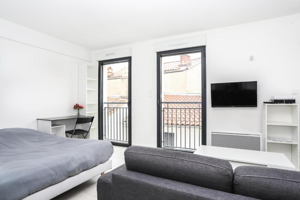 a bedroom with a bed and a couch and a tv at 204 - Appartement Moderne et Lumineux - Jeanne d'Arc, Toulouse in Toulouse