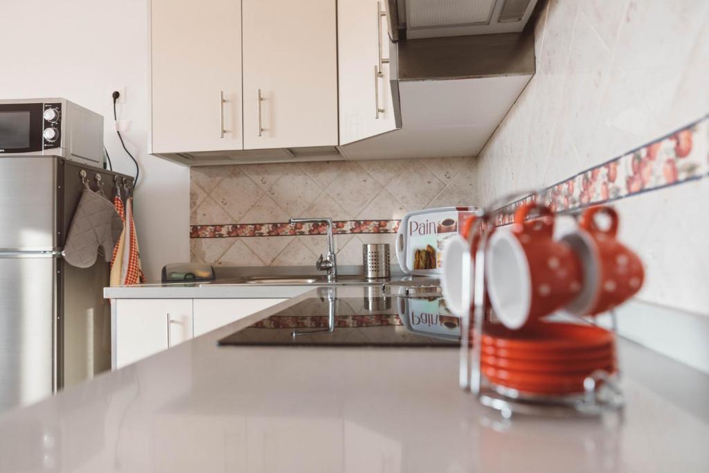 una cocina con armarios blancos y tazas rojas en la encimera en Apartamento Cuesta del salado, en Caleta de Sebo