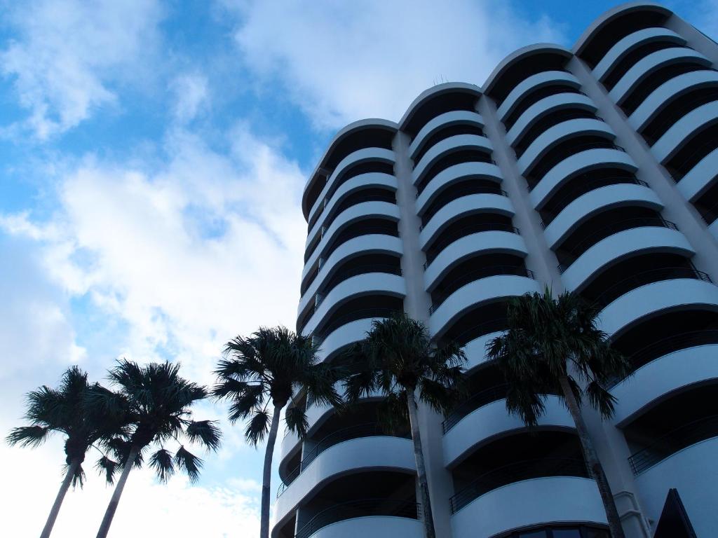 een hoog gebouw met palmbomen ervoor bij Hotel Sunset Hill in Onna