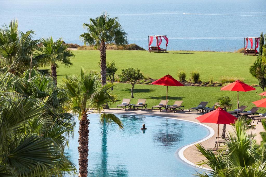 a swimming pool with palm trees and chairs and umbrellas at Cascade Wellness Resort in Lagos