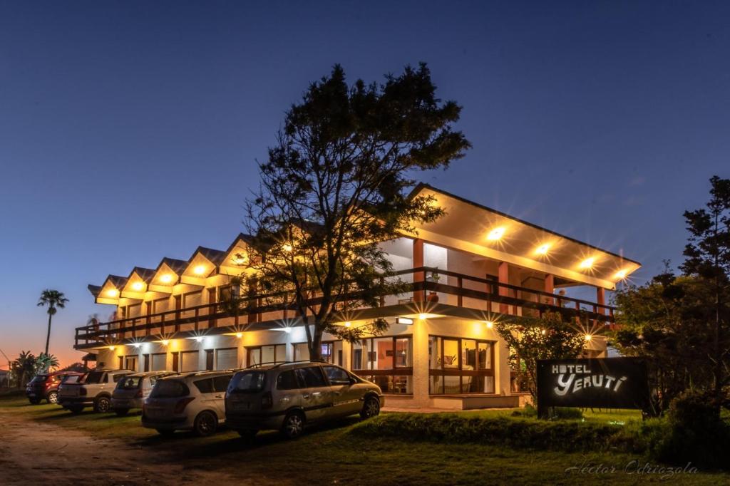 un edificio con coches aparcados delante de él por la noche en Hotel Yeruti, en La Paloma