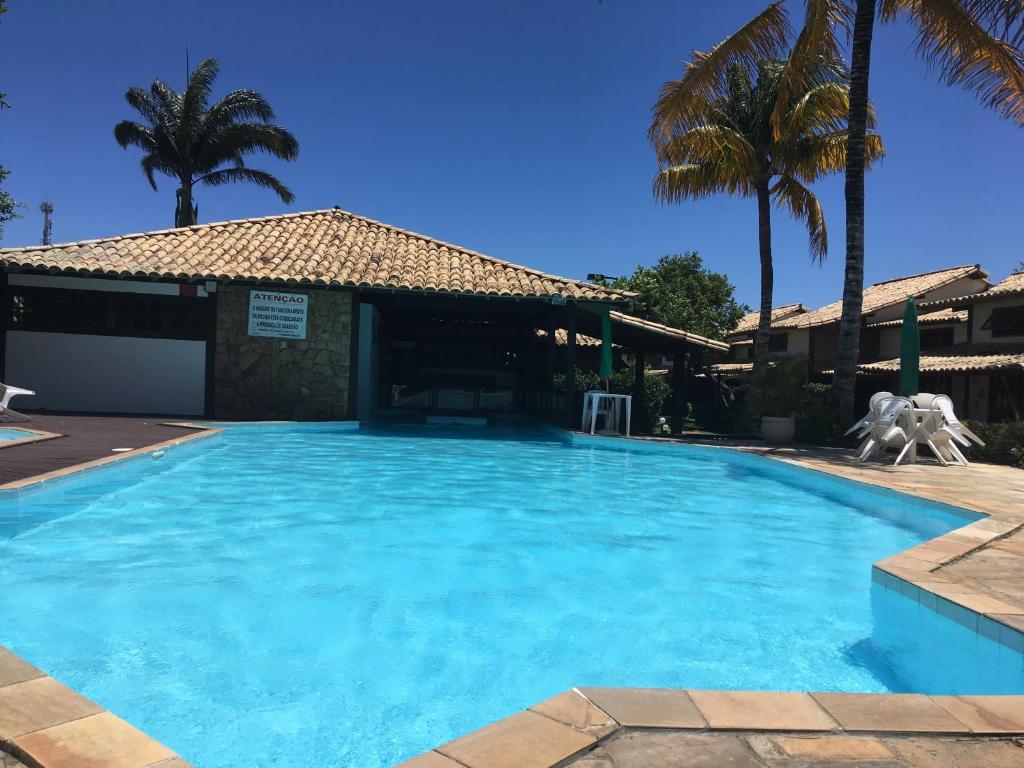 ein großer blauer Pool mit Palmen im Hintergrund in der Unterkunft A Casa - com 3 quartos e até 7 Hóspedes in Búzios