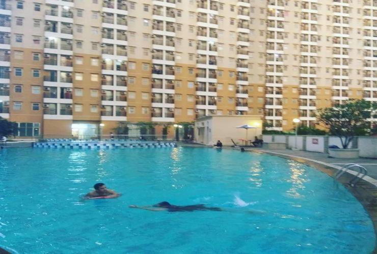 una mujer nadando en una piscina en un edificio grande en QQ Apartment Margonda Residence 2 en Depok