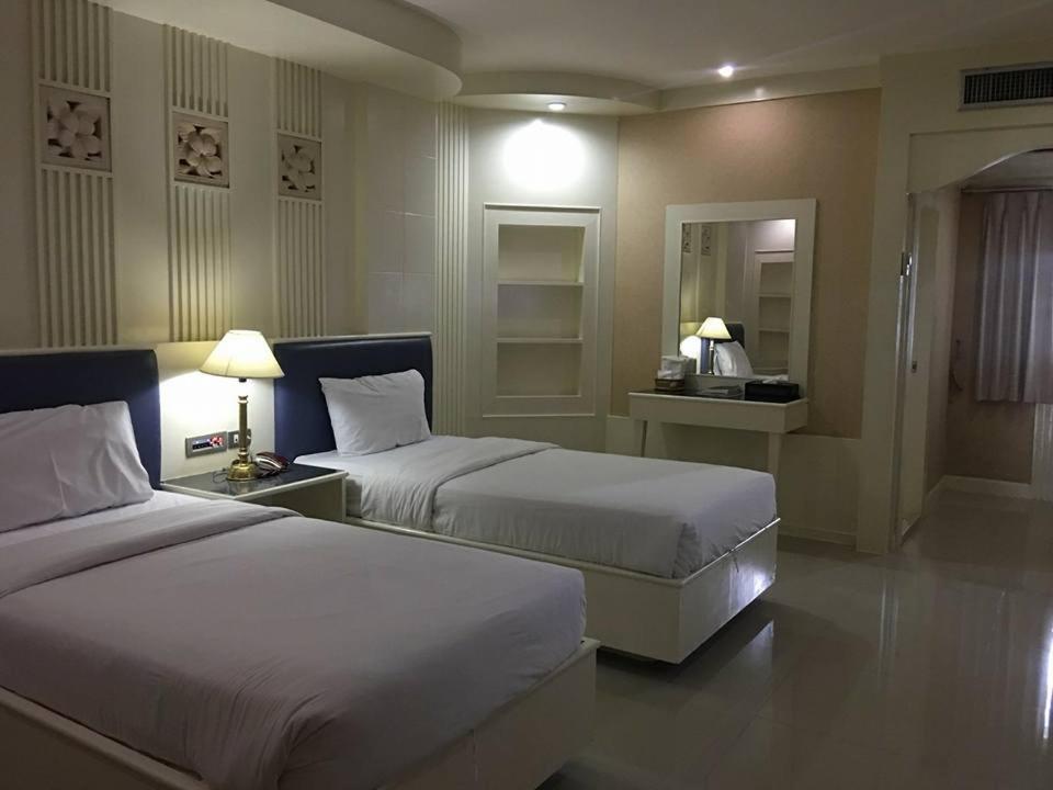 a hotel room with two beds and two lamps at The Rich Hotel in Nonthaburi