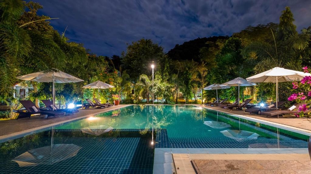 a swimming pool with chairs and umbrellas at night at Kep Bungalows in Kep