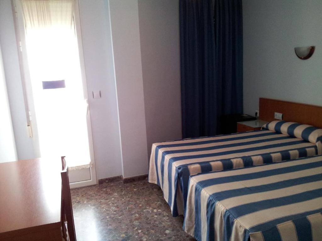 a hotel room with two beds and a window at Hotel Costa San Antonio in Cullera