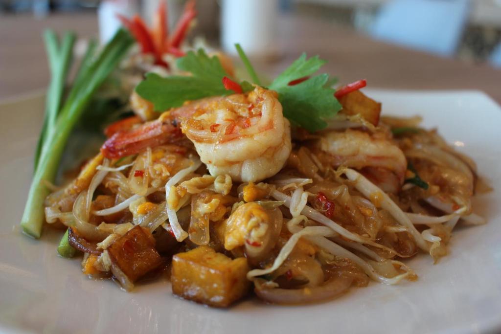 A plated noodle dish with shrimp is presented as a hotel dining offering.