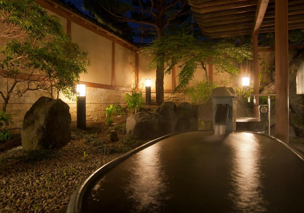a pool in a garden at night with lights at Oike Hotel in Fujikawaguchiko
