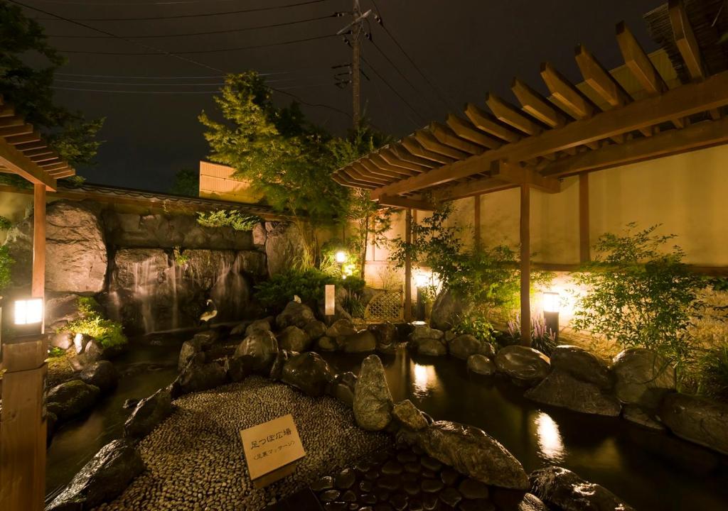 a pond in a garden at night with lights at Oike Hotel in Fujikawaguchiko
