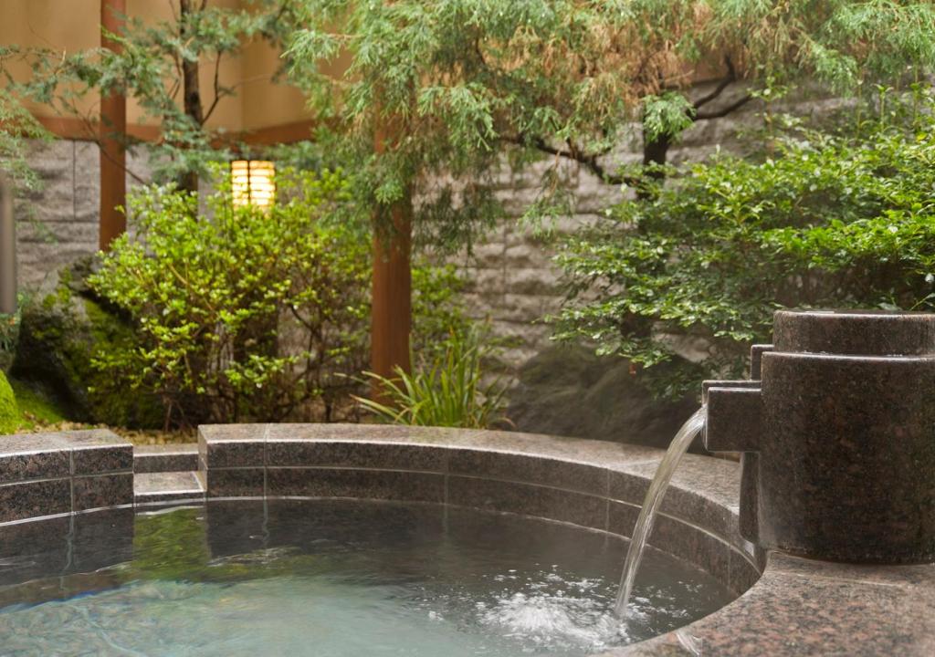 a swimming pool with a fountain in a garden at Oike Hotel in Fujikawaguchiko