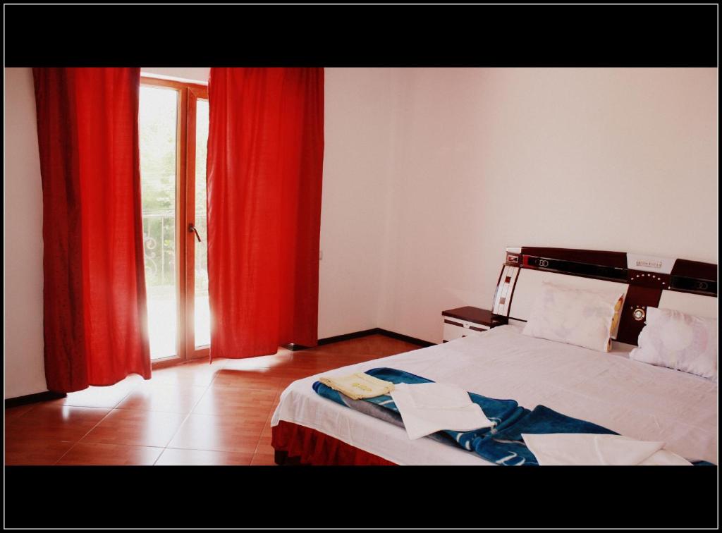 1 dormitorio con 1 cama con cortinas rojas y ventana en Vila Silvia, en Eforie Sud