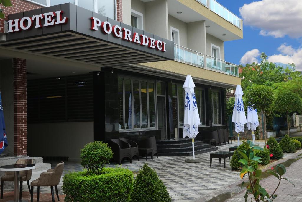 a hotel with chairs and umbrellas in front of it at Hotel Pogradeci in Pogradec