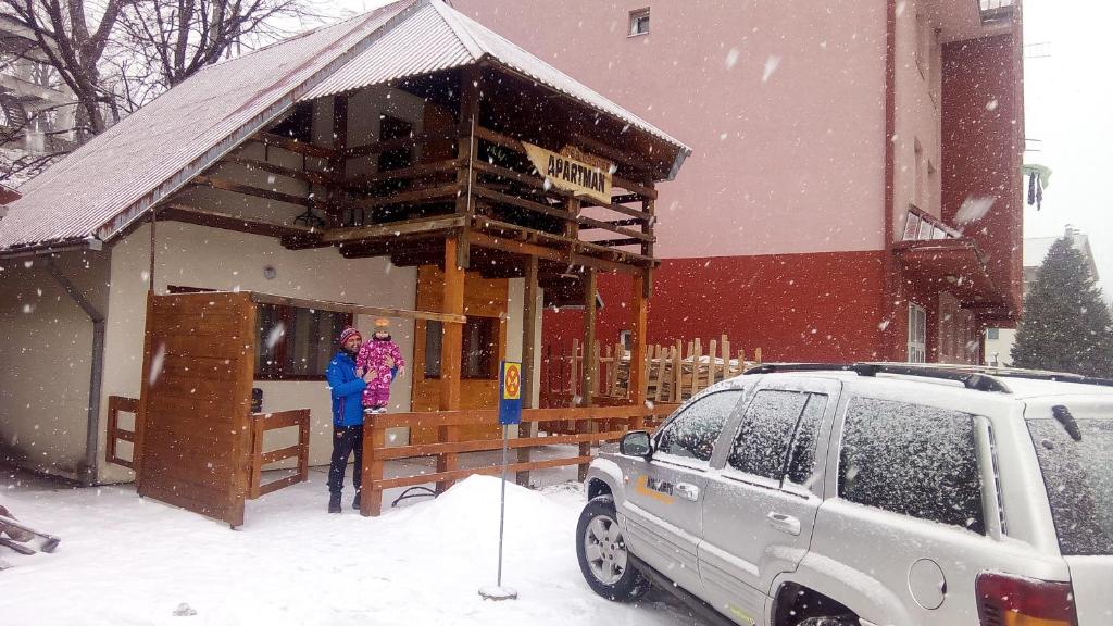 a woman standing outside of a building in the snow at Apartments Life in Kolašin