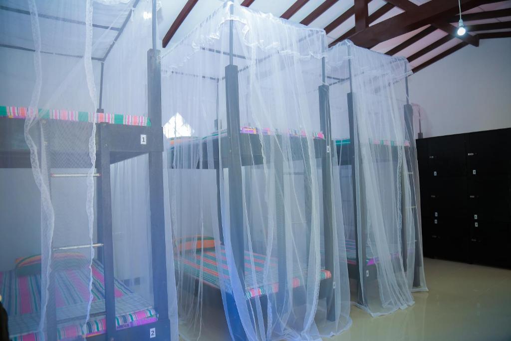 um quarto com uma cama com cortinas em Hikka Surf Hostel em Hikkaduwa