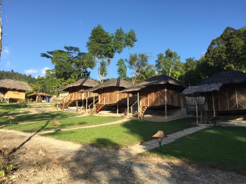 a group of huts with grass roofs on a field at Backpacker's Hill Resort in San Vicente