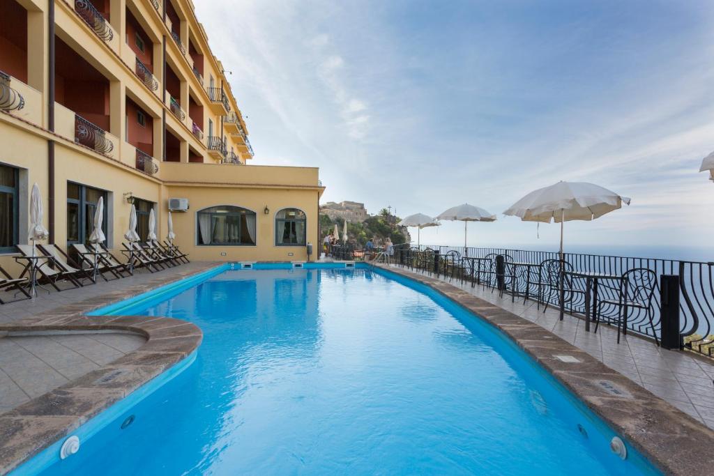 una piscina con sillas y sombrillas junto a un edificio en Hotel Sole Castello, en Taormina