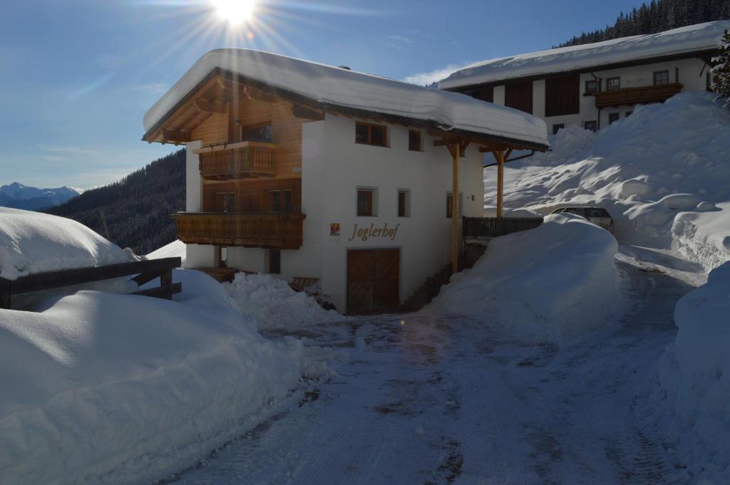 a building covered in snow with the sun behind it at Joglerhof in Racines