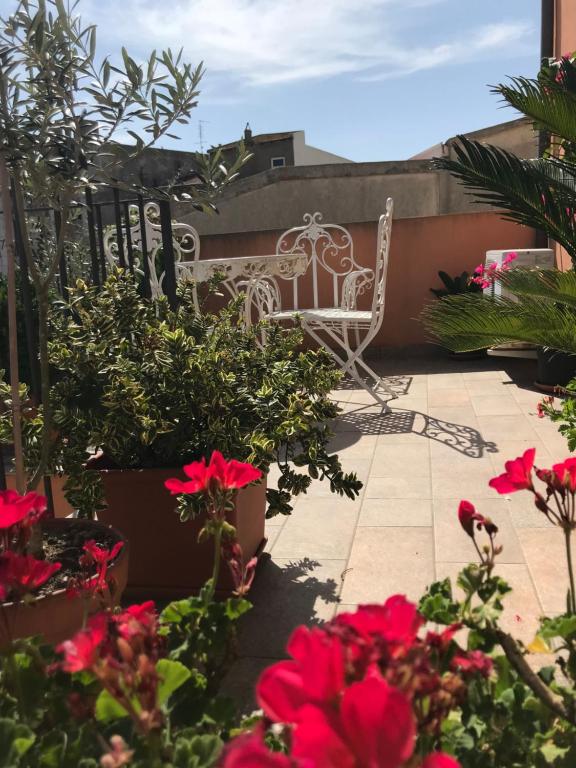 un patio con una silla blanca y flores rojas en Bed & Breakfast La Casa Antica, en Macomer