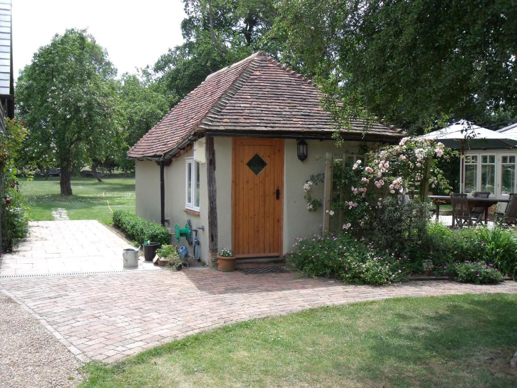 a small house with a wooden door in a yard at Wilderness B&B 3 Self Contained Rooms Nr Sissinghurst in Headcorn