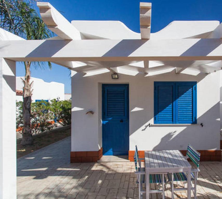 a white house with a blue door and a table at Petruso Resort in Balestrate