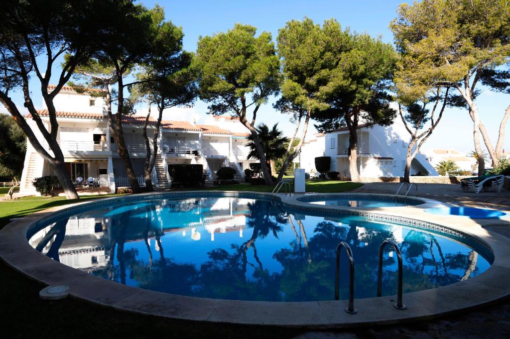 una grande piscina con alberi sullo sfondo di AMANECER EN PORT D´ADDAIA a Es Mercadal